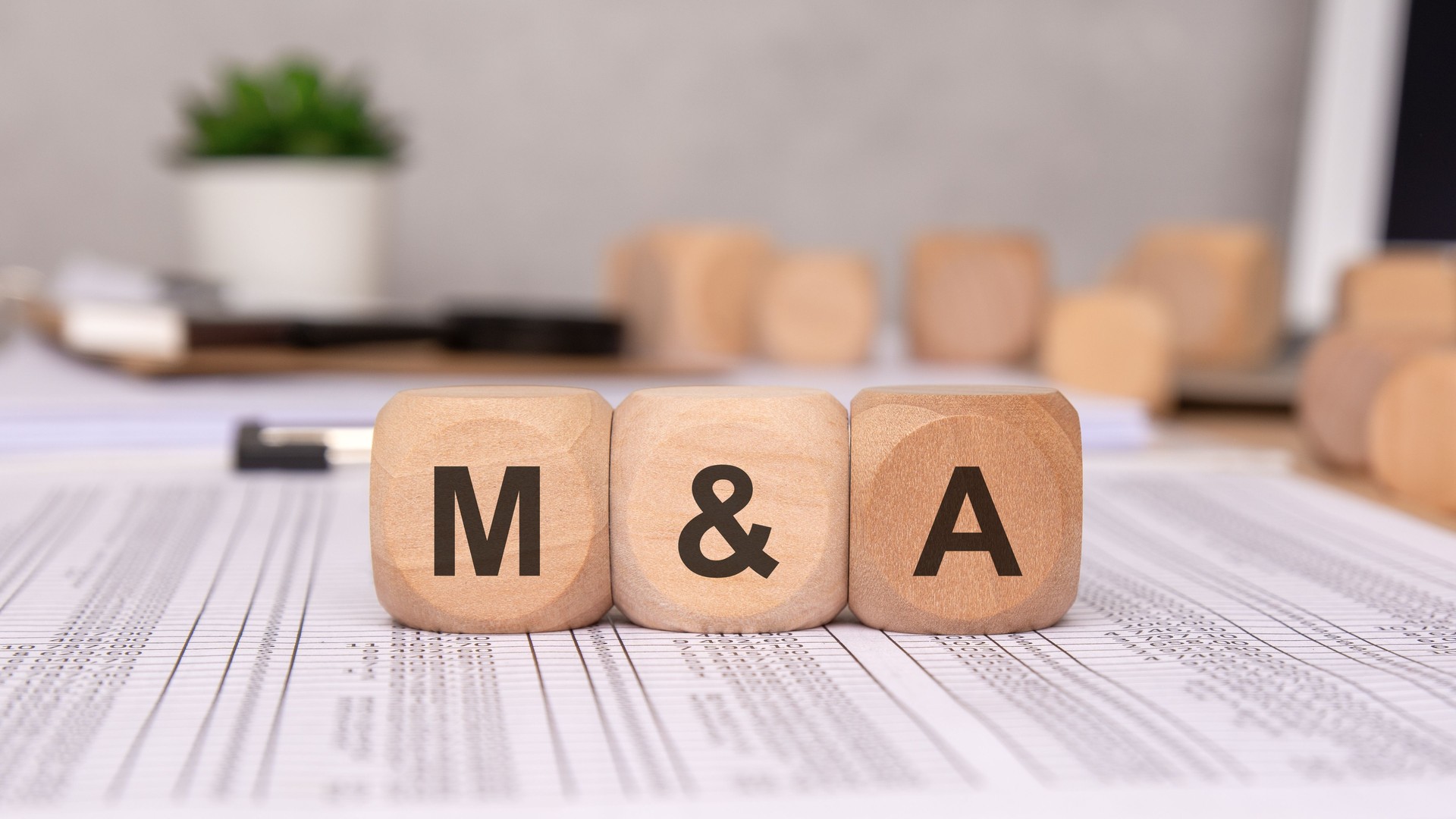 wooden blocks with 'M and A' letters on financial documents, symbolizing mergers and acquisitions